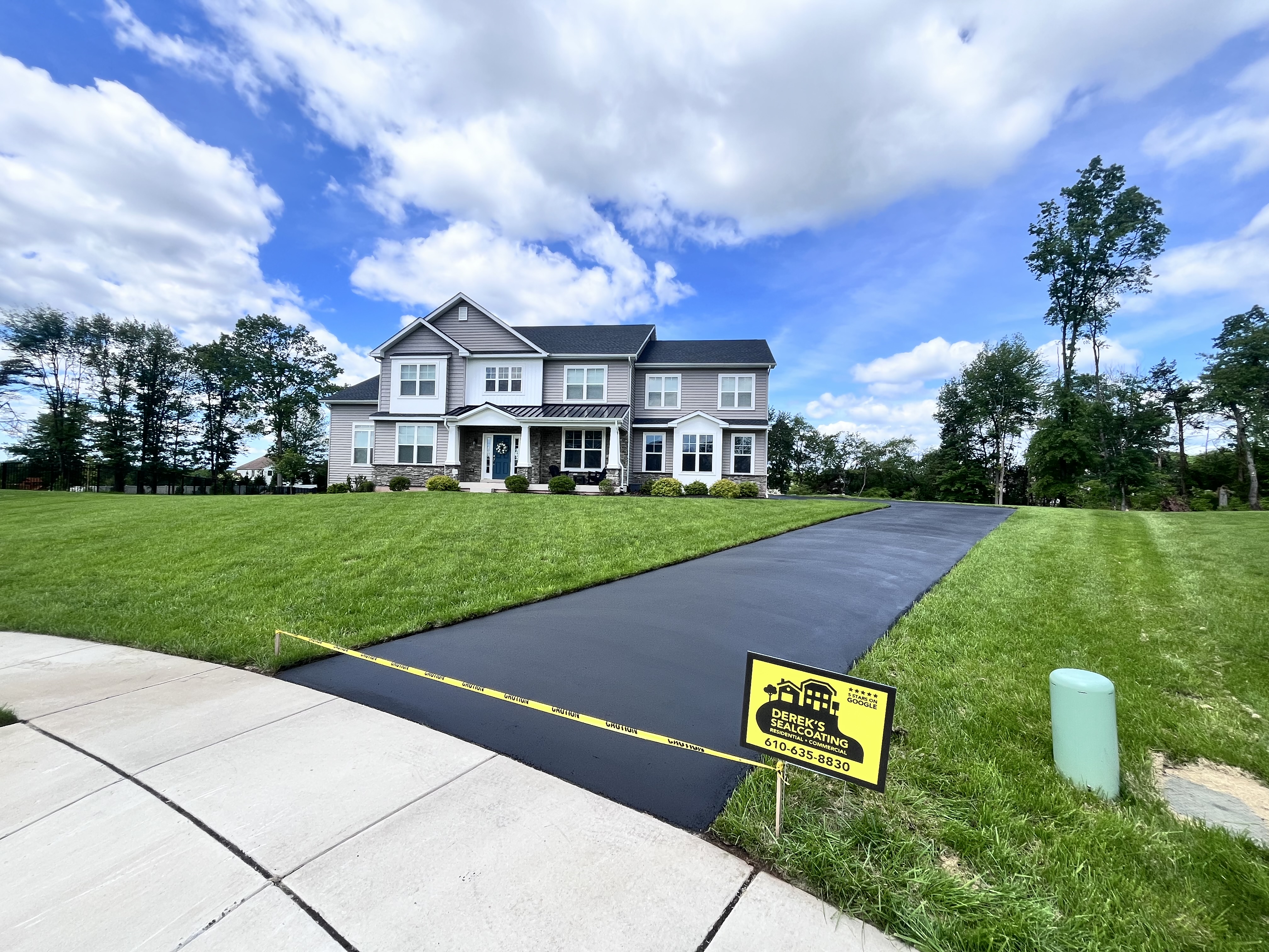 Freshly sealed residential driveway — Derek's Sealcoating yard sign visible, Collegeville PA