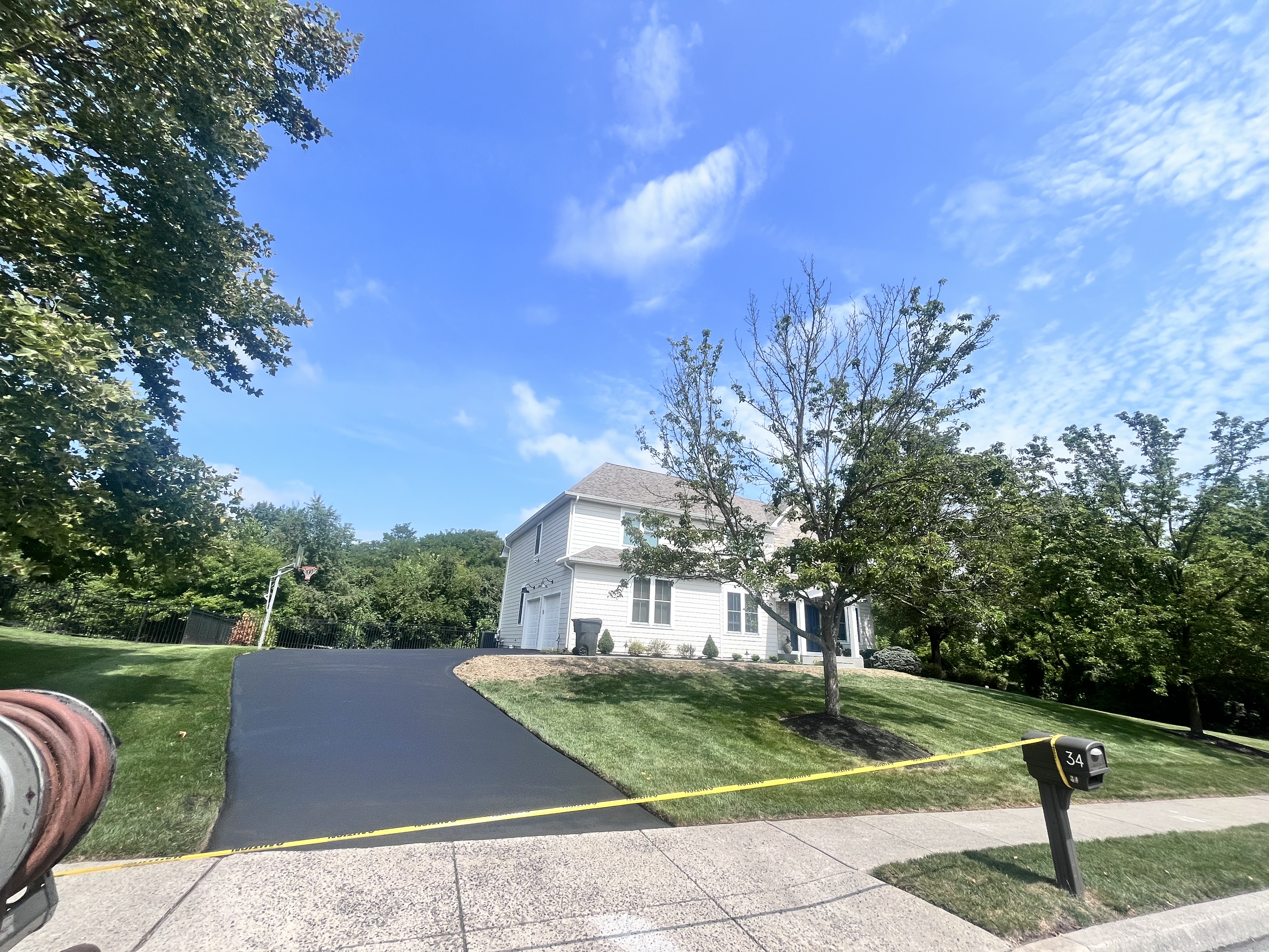 Curved driveway sealcoating — white colonial home Montgomery County