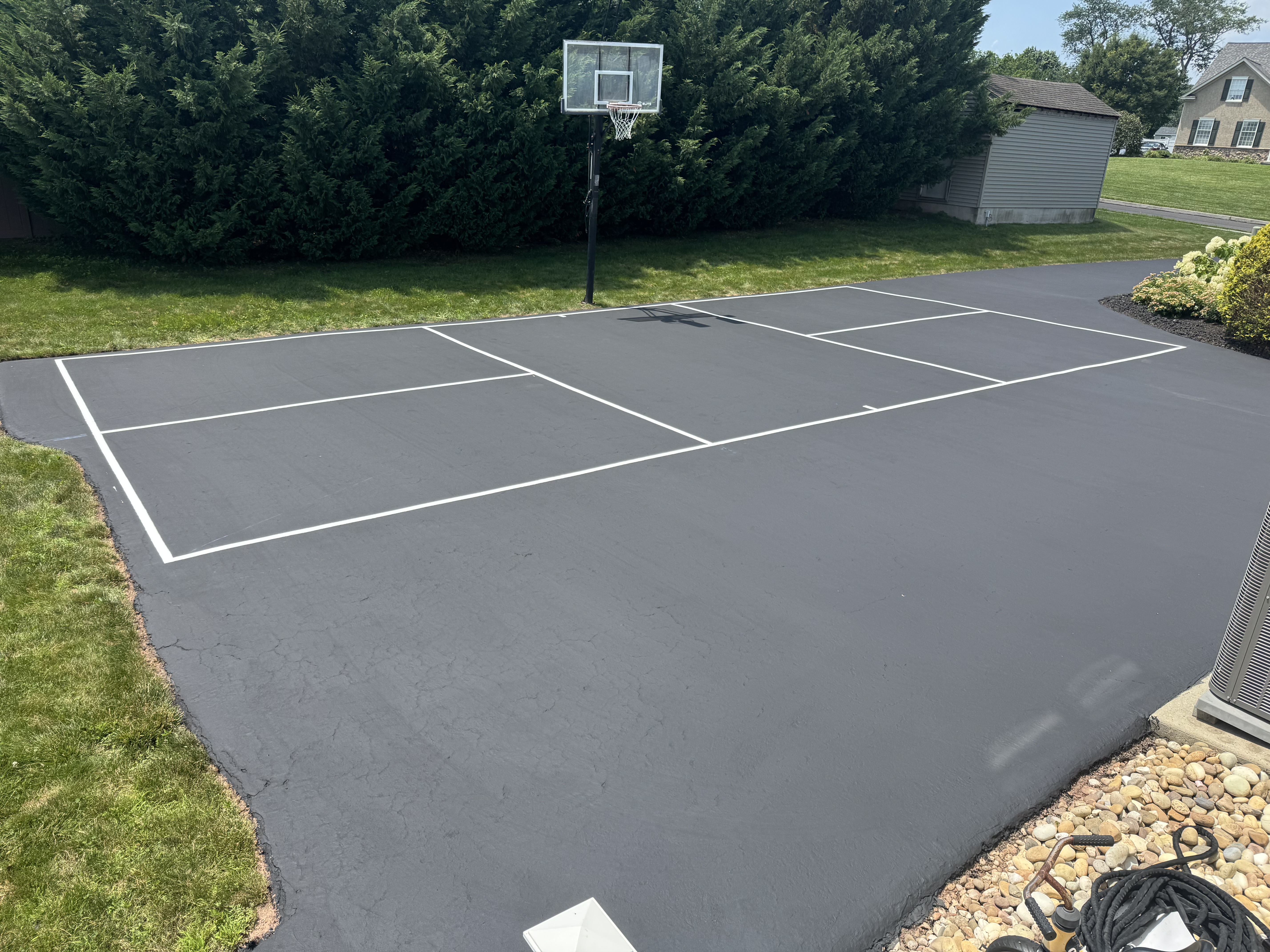 Freshly sealed and line-striped pickleball court — residential sport court